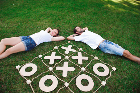 Friends rest and play tic-tac-toe on the green grass.の写真素材