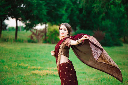 Portrait smiling of beautiful indian girl. Young woman model with red jewelry set .の写真素材