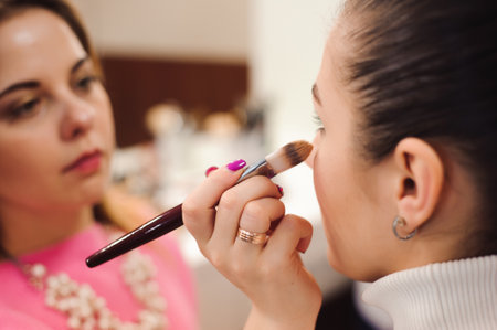 Make up artist doing professional make up of young woman. Beauty shcool.の写真素材