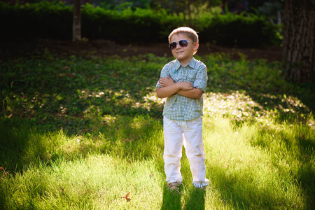 Happy little boy with sunglasses in the garden.の写真素材