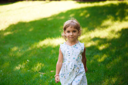 Sweet little girl outdoors with curly hair in the wind.の写真素材