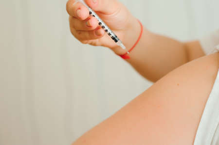 Insulin injection close-up. Girl injects insulin into his hand independently. Diabetesの写真素材