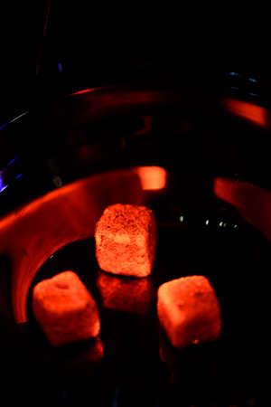 Bowl of the hookah with red hot coals in the hands of a hookah on a dark background.の写真素材
