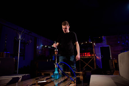 Man makes hookah. Modern hookah with coconut charcoal for relax and shisha smoke.の写真素材