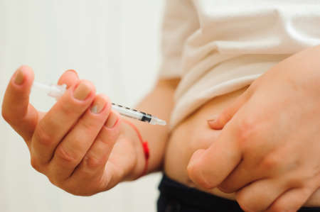 Medicine, diabetes, glycemia, health care and people concept - close up of woman hands making injection with insulin pen or syringe.の写真素材