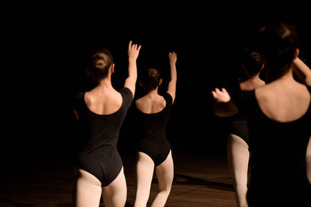 A choreographed dance of a group of graceful pretty young ballerinas practicing on stage in a classical ballet school.の写真素材