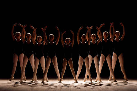 A choreographed dance of a group of graceful pretty young ballerinas practicing on stage in a...
