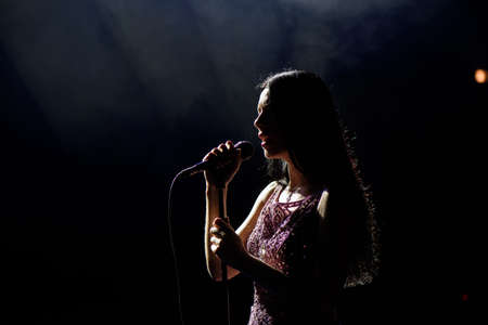 Portrait of beautiful singing woman on dark background.の写真素材