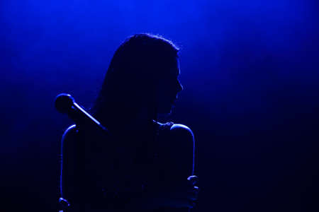 Portrait of beautiful singing woman on dark background.