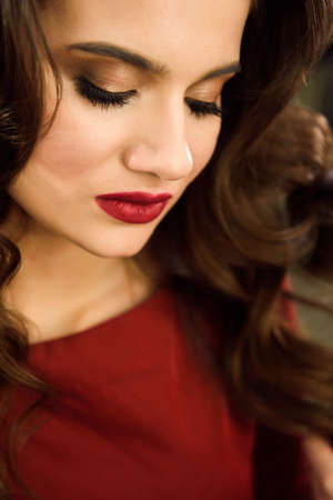 Hairdresser makes hairstyle girl with long hair in a beauty salon. Create curls with curling irons. Professional hair care.の写真素材