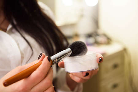 Woman applying cosmetic powder with tassel, skin care concept.の写真素材