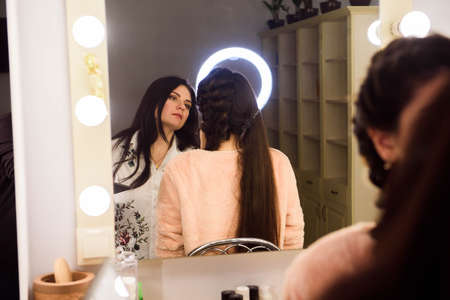 Process of making makeup. Make-up artist working with brush on model face. Portrait of young woman in beauty saloon interior. Applying tone to skin.の写真素材