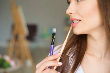 Portrait of talented young woman painting picture in art studio with inspiration.の写真素材