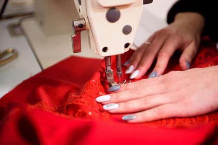 Seamstress is working sewing clothes in sewing machine, hands closeup.の写真素材