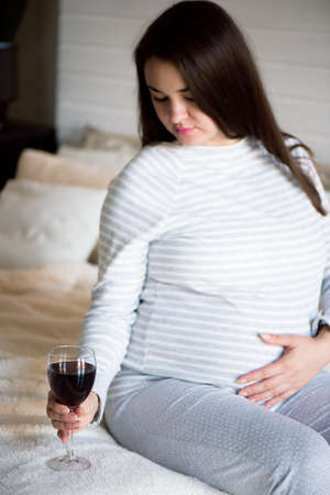 Pregnant woman drinking glass of red wine.の写真素材