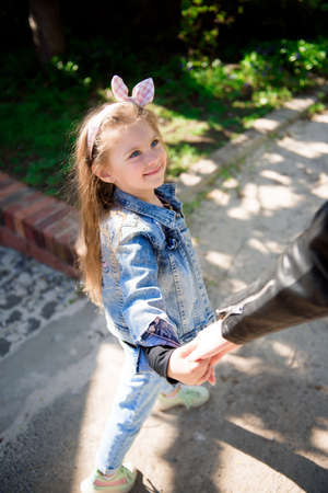 Beautiful young mother and her adorable little daughter, cute little curly girl playing and walking...