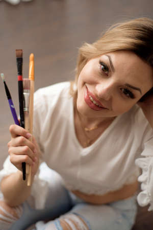 Woman artist drawing her picture on canvas with oil colors at homeの写真素材