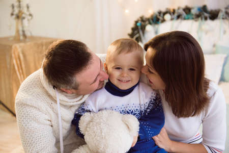Christmas family. Happy mom,dad and little son lying on the bed. Enjoyng love hugs, holidays people.の写真素材