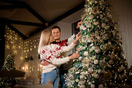 Happy couple decorating Christmas tree together at home.の写真素材