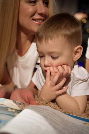 Happy family mother father and child lying by the New Year tree on Christmas Eve.の写真素材