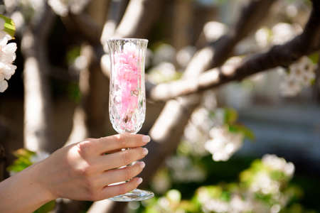 A glass with flowers inside against the background of a blooming spring garden.の写真素材