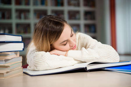 A tired student is studying in the school library.の写真素材