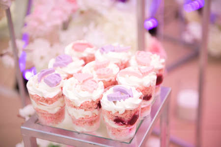 Candy bar. White wedding cake standing of festive table with deserts, tartlet and cupcakes. Wedding.