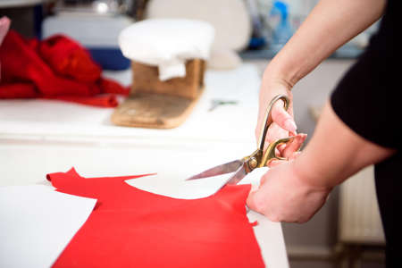 Tailor working with cloth at table in atelier.