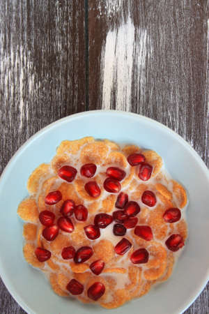 Corn flakes with pomegranate isolated on wood backgroundの写真素材