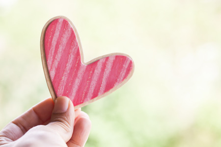 hand holding pink wooden heartの写真素材