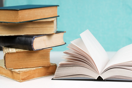 Open book, stack of hardback books on table. Back to school. Copy space.