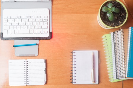 Office desk table with computer, supplies, flowerの写真素材