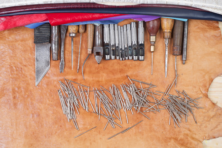Leather craft tools on a leather background. Craftsman work desk . Piece of hide and working handmade tools on a work table. Top view. Copy space.の写真素材