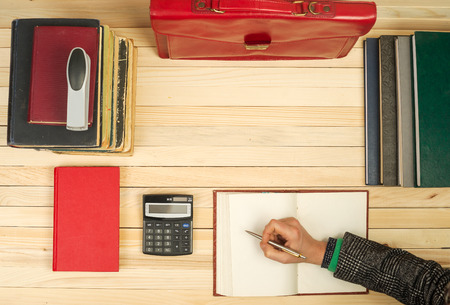Financial concept. Business partners discuss profit and losses, analyzing financial results. On a wooden table books, documents, calculator, stapler, red briefcase.の写真素材