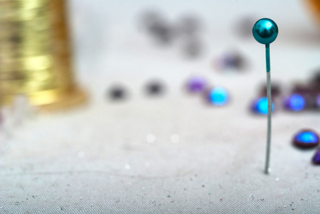 Sewing textile or cloth. Work table of a tailor. Detail of a needle with thread in the workroom reel of thread, and natural fabric. . Shallow depth of field. Focus on needle.の写真素材