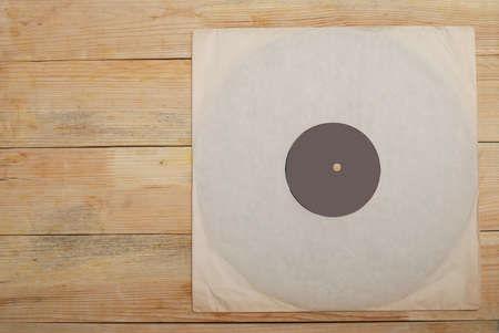 Retro styled image of a collection of old vinyl record lp's with sleeves on a wooden background. Copy space. Top view.の写真素材