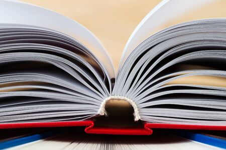 Open book, stack of hardback books on wooden table. Back to school. Copy space.