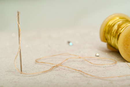 Sewing textile or cloth. Work table of a tailor. Detail of a needle with thread in the workroom reel...