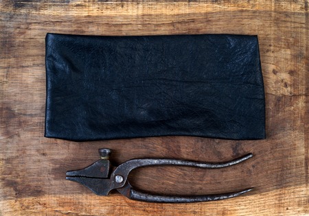 Leather craft tools on a wooden background. Craftmans work desk . Piece of hide and working handmade tools on a work table. Top view.の写真素材