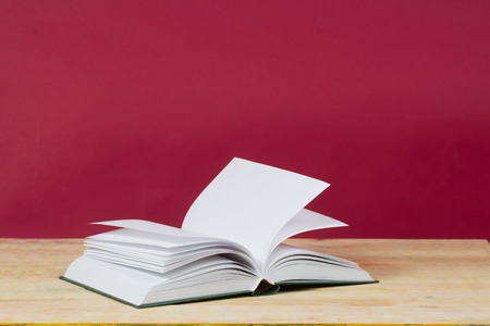 Open book on wooden table. Back to school. Red background. Copy space.の写真素材