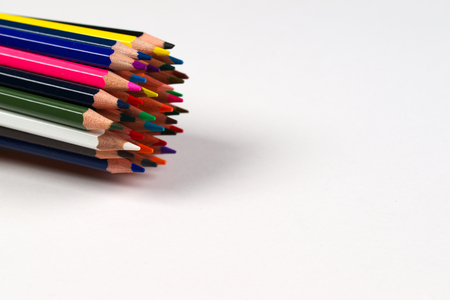 Multicolored pensils and elastic in the box on the white paper. Back to school. Copy space. Top view.の写真素材