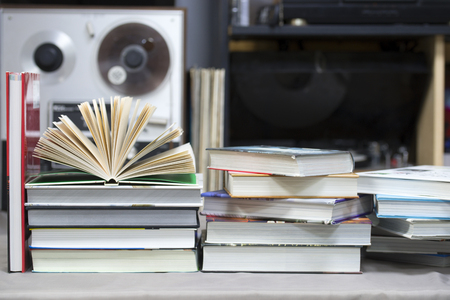 Open book, stack of hardback books on table. Top view.の写真素材