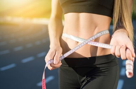 Woman outdoors measures the figure on the race site. Healthy lifestyle concept. Sportswear.の写真素材