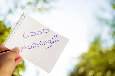 Man holds a notebook on a sunny day that says good morning.の写真素材