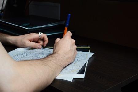 Artist encircles pen sketch of a tattoo on the desktop . The artist draws a sketch.の写真素材
