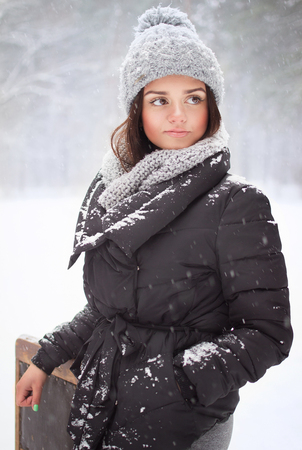 Beautiful brunette in a black jacket standing in a winter forestの写真素材