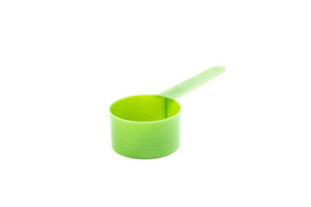 Green plastic measuring spoon on whiteの写真素材