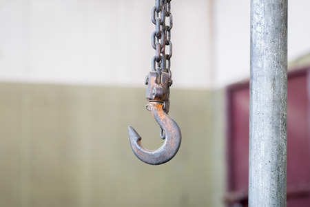 Metal hook hanging on chain in factoryの写真素材