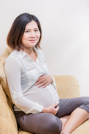 Pregnant woman relaxing at home on vintage sofaの写真素材