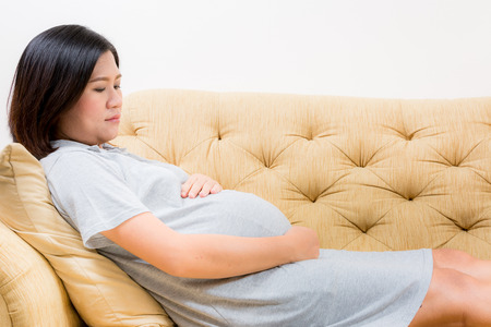 Pregnant woman relaxing at home on vintage sofaの写真素材